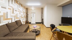 Una sala de estar moderna con un sofá, una mesa de centro redonda y un televisor.