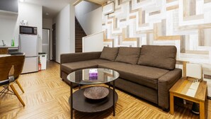 Una sala de estar moderna con un sofá modular, una mesa de centro de vidrio y suelo de madera.