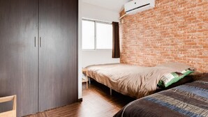 Un dormitorio con cama, armario, pared de ladrillo y equipo de aire acondicionado.