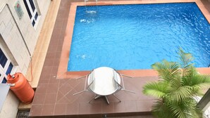 A rectangular swimming pool with a metal ladder, surrounded by tiled flooring and a metal table with chairs. - Sky Rock Hotels (Lagos)