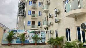 A multi-story building with balconies, air conditioning units, and a mural advertising a swimming pool. - Sky Rock Hotels (Lagos)