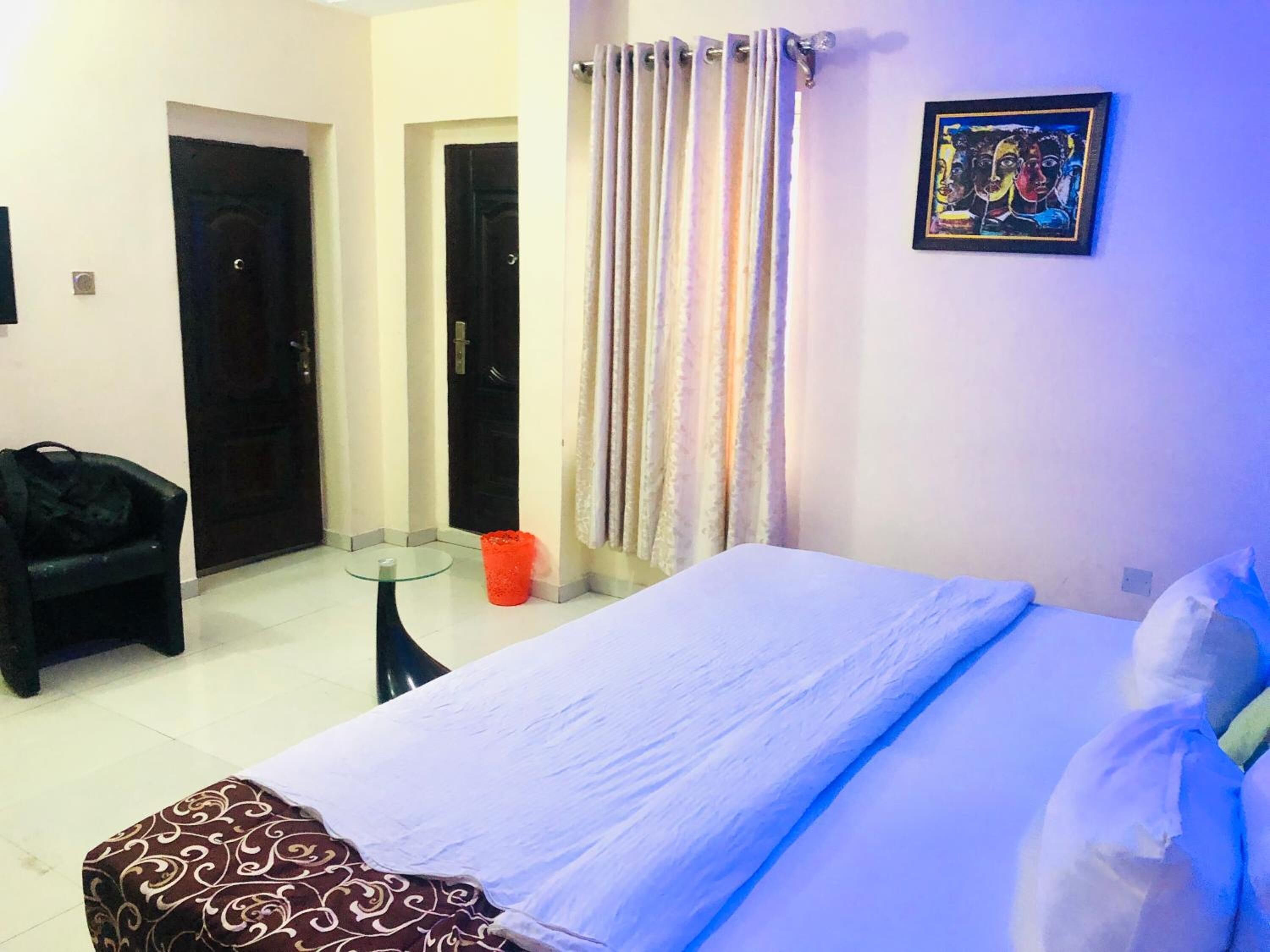 Une chambre à coucher avec un lit, une chaise, une petite table et une porte.