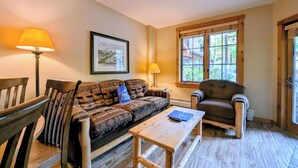 A cozy living room with a sofa, chairs, a coffee table, and a window with a view of trees. - Summer Base | Patio, Pool & Hot Tub (keystone)