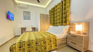 Un dormitorio con cama, mesita de noche, lámpara y ventilador de techo.