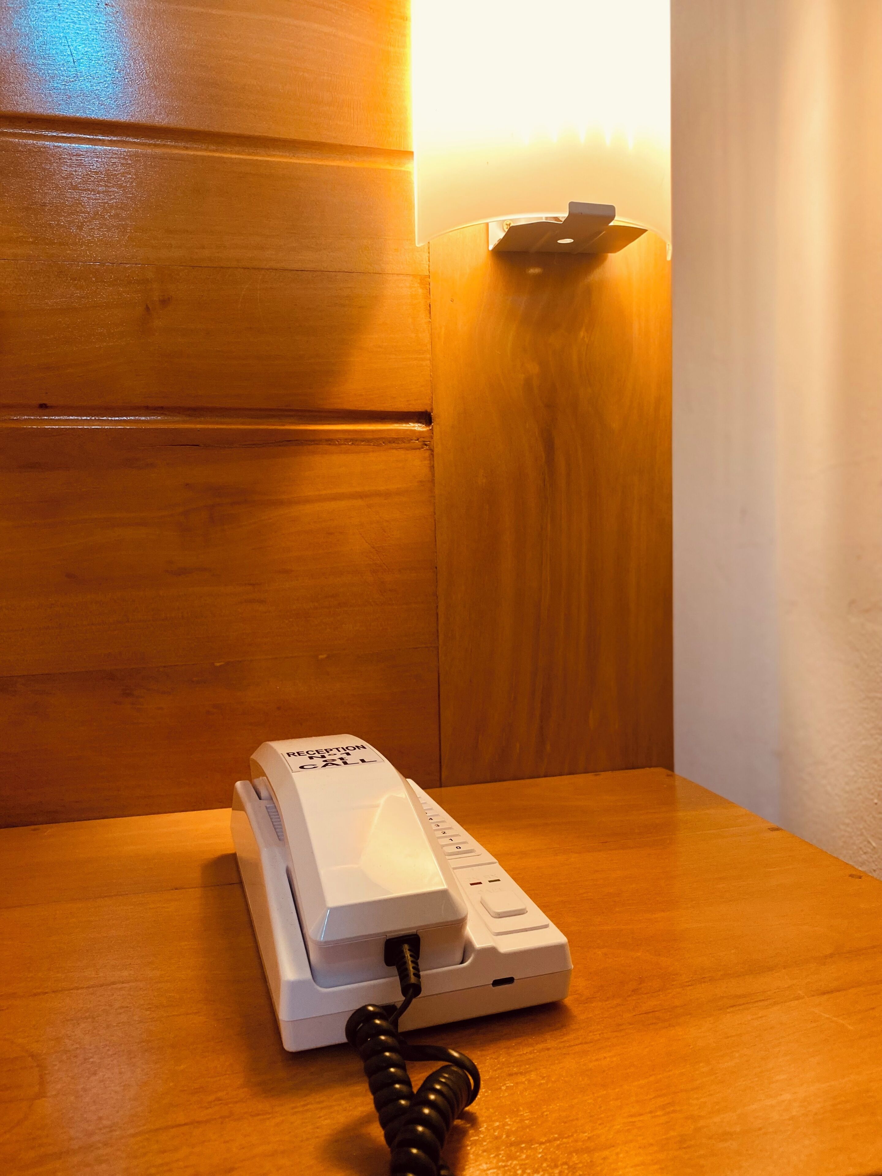 A reception phone on a wooden table in a room with wooden paneling.