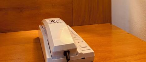 A reception phone on a wooden table in a room with wooden paneling.