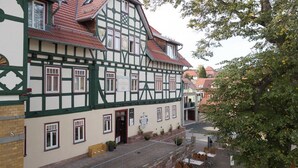 A traditional half-timbered building with a red-tiled roof, multiple windows, and a small outdoor seating area with tables and chairs.