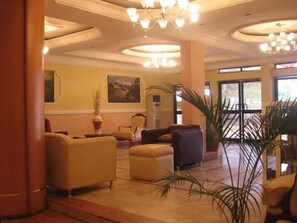 A lobby with a large seating area, a chandelier, and a painting on the wall. - Roban Hotel Enugu (Enugu)