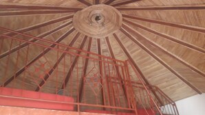 A wooden ceiling with a central circular design and red metal railings. - Auberge Le Dakan (Mbour)