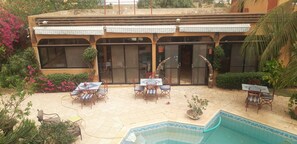 Un edificio con zona de piscina, mobiliario exterior y terraza cubierta.