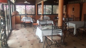 A restaurant with tables and chairs, large windows, and a tiled floor. - Auberge Le Dakan (Mbour)