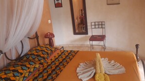 A bedroom with a bed, a chair, and a mirror. - Auberge Le Dakan (Mbour)