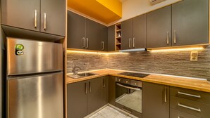 A modern kitchen with stainless steel appliances, dark cabinetry, and a wooden countertop. - Amoudara Suites (Malevizi)