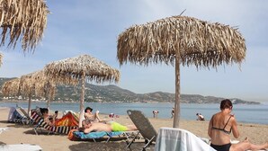 A beach with thatched umbrellas and lounge chairs. - Amoudara Suites (Malevizi)