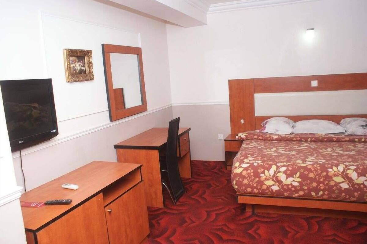 Une chambre d’hôtel comprenant un lit, un bureau, une chaise, une télévision et un miroir.