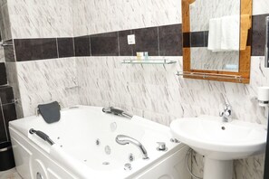 Une salle de bain moderne avec une baignoire blanche, un lavabo et un miroir.