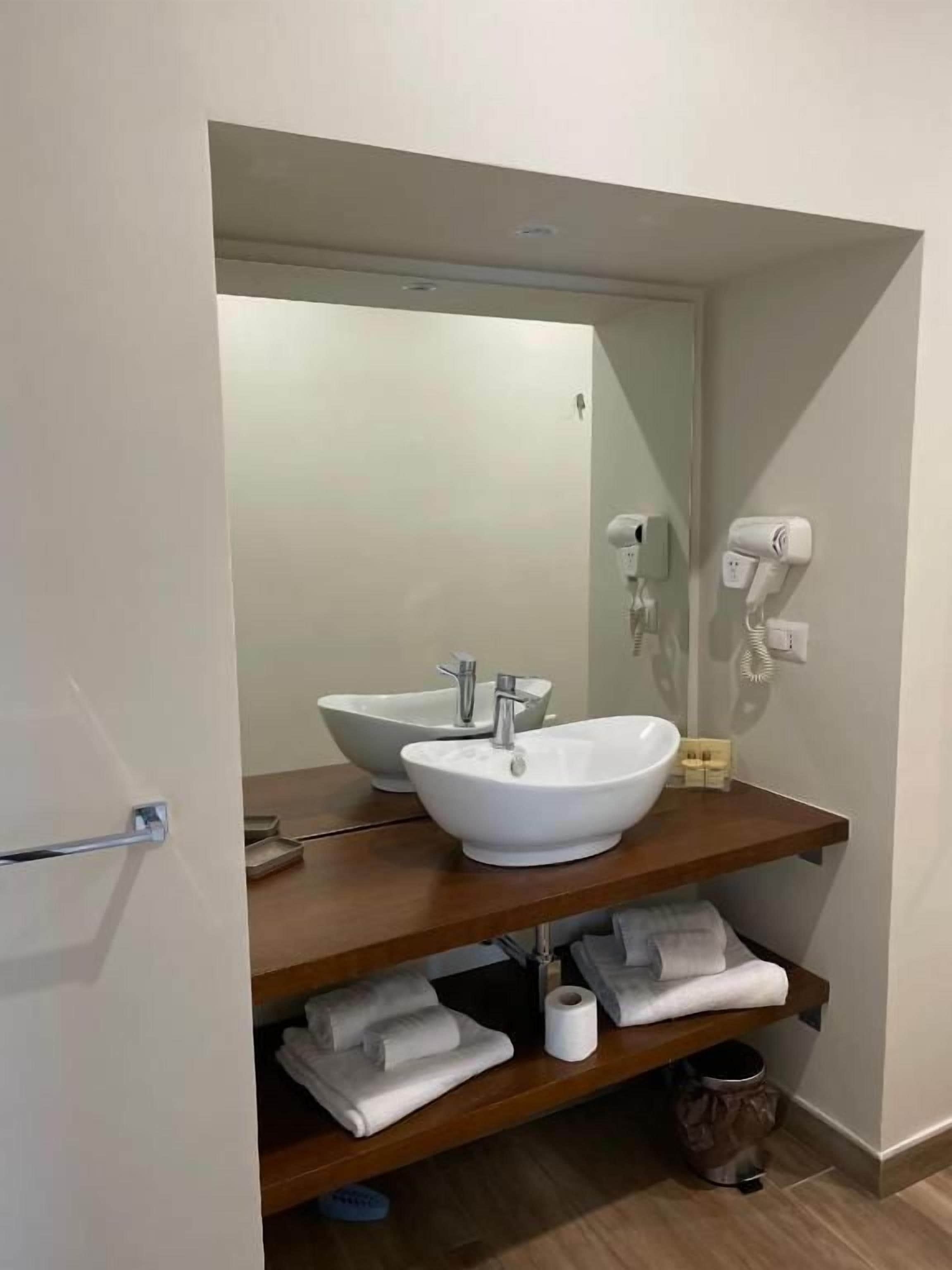 A bathroom with a white sink, a mirror, and a towel rack.