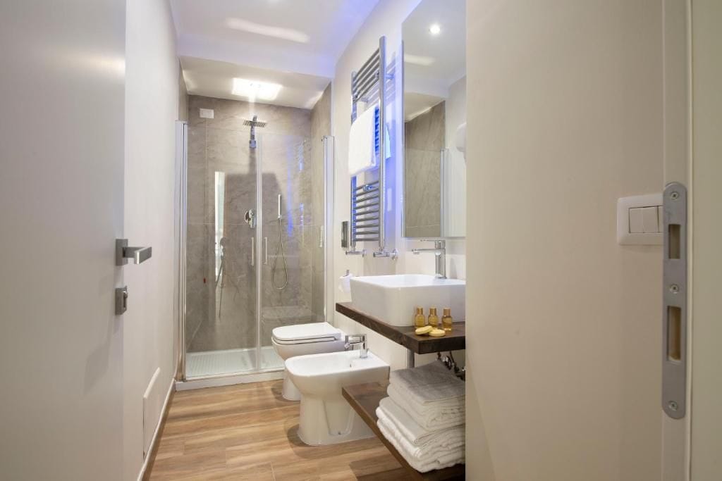 Un baño moderno con ducha envuelta en vidrio, inodoro blanco, bidé y tocador con espejo.