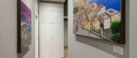 Un couloir avec deux tableaux, une armoire blanche et une porte.