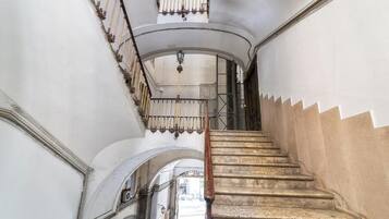 Una escalera con barandilla de madera y pasamanos de metal que lleva a un piso superior.