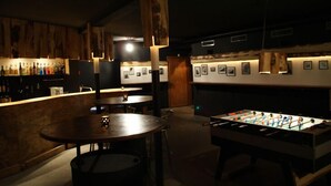 A dimly lit bar area with a foosball table and a bar counter.
