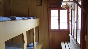 A bunk bed room with wooden walls and a window.