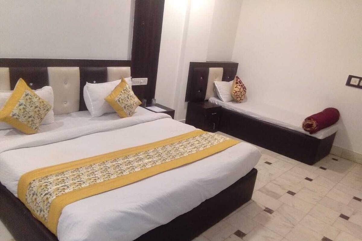 A double bed with a white and yellow bedspread, two nightstands, a red towel, and a tiled floor.