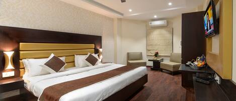 Una habitación de hotel con una cama grande, un ventilador de techo, un televisor y un escritorio con una silla.
