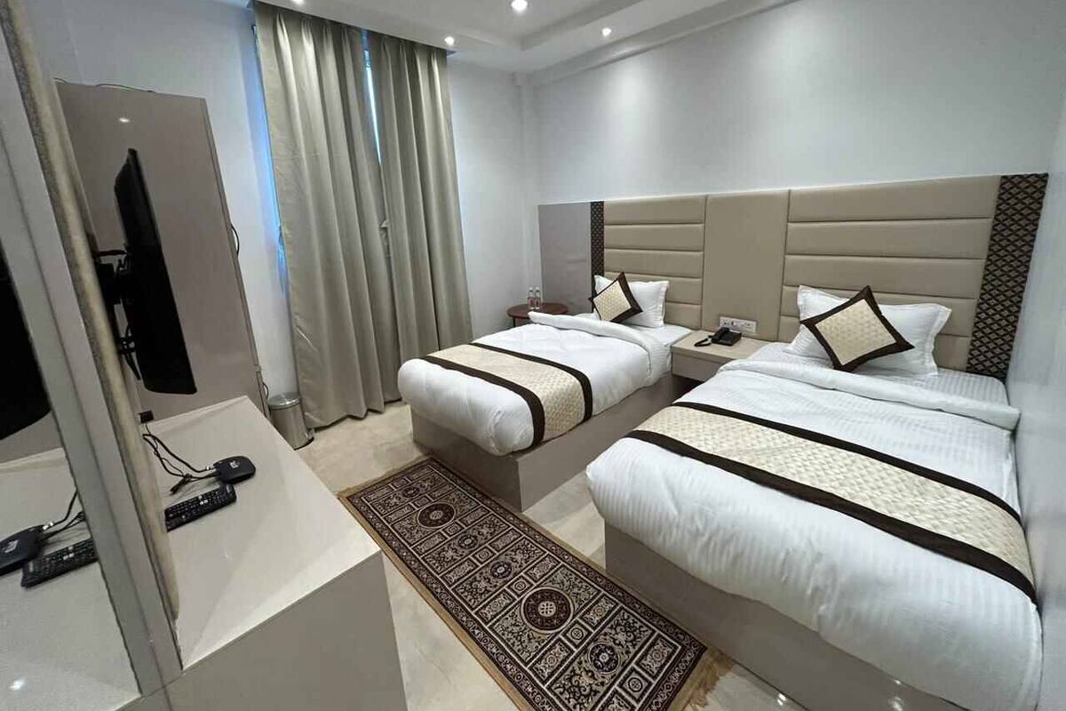 A hotel room with two beds, a desk with a computer, and a bathroom.
