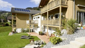 Un edificio de dos plantas con balcones, piscina y un jardín con fuente.