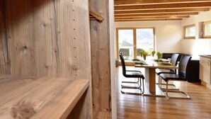 Una cocina moderna con vigas de madera, un comedor con sillas negras y ventanas amplias.