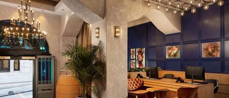 A modern office space with a large desk, multiple chairs, a chandelier, and artwork on the walls.