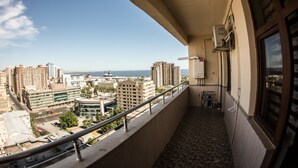 A balcony with a view of a cityscape, including high-rise buildings and a body of water.