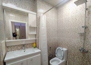 A bathroom with a white sink, a toilet, a shower, and a mirror. - Bakuvi Tourist Apartment B074 (Baku)