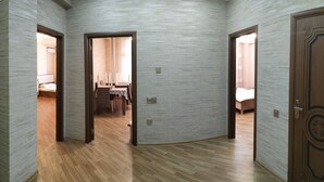 A hallway with wooden flooring and light-colored walls, leading to three bedrooms with wooden doors. - Bakuvi Tourist Apartment B038 (Baku)