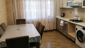 A compact kitchen with a dining area, wooden flooring, and a washing machine. - Bakuvi Tourist Apartment B038 (Baku)