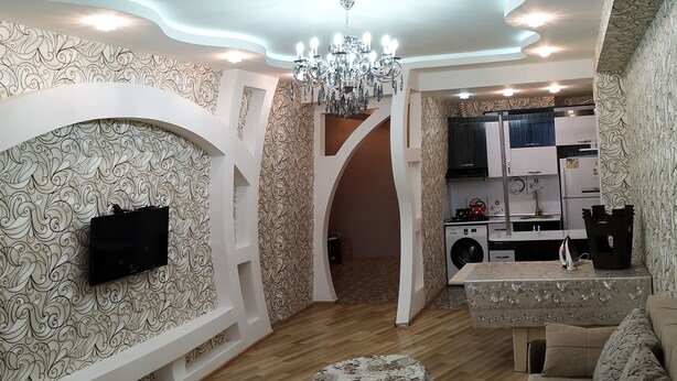 A modern living room with a TV, sofa, and a dining area with a table.