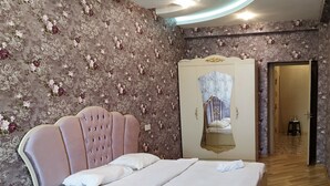 A bedroom with a large bed, a wardrobe, and a mirror.