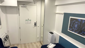A hotel room with a bed, a desk, a chair, a radiator, and a wall-mounted artwork.