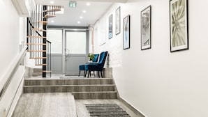 A modern interior with a wooden staircase, a seating area with a blue chair, and framed artwork on the walls.