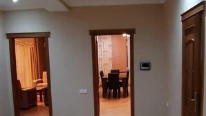 A spacious room with a wooden floor, a dining area with a table and chairs, and a door leading to another room. - Bakuvi Tourist Apartment B022 (Baku)
