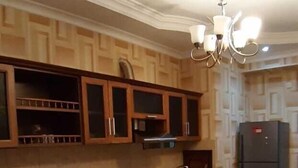 A kitchen with wooden cabinets, a built-in washing machine, a dining table, and a chandelier. - Bakuvi Tourist Apartment B022 (Baku)