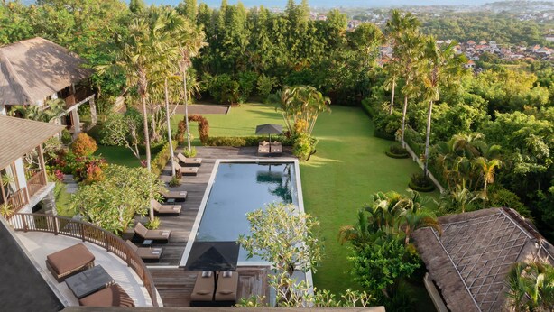 A resort with a swimming pool, lounge area, and a view of the ocean and mountains. - Villa Uma Nina by Nakula (Nusa Dua)