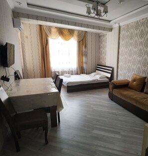 A hotel room with a bed, a sofa, a dining table, and a TV. - Bakuvi Tourist Apartment B004 (Baku)