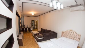 Una habitación de hotel compacta con cama, sofá, una mesita y un escritorio.