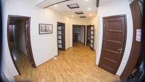 Un pasillo con suelo de madera, techo con iluminación empotrada y una puerta a la derecha.