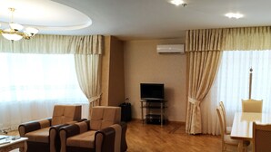 A living room with a sofa set, a TV, a dining table with chairs, and a patterned rug. - Bakuvi Tourist Apartment B096 (Baku)