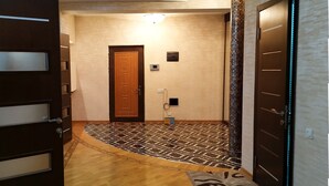 A hallway with wooden flooring, a patterned rug, and a door with a light strip. - Bakuvi Tourist Apartment B096 (Baku)