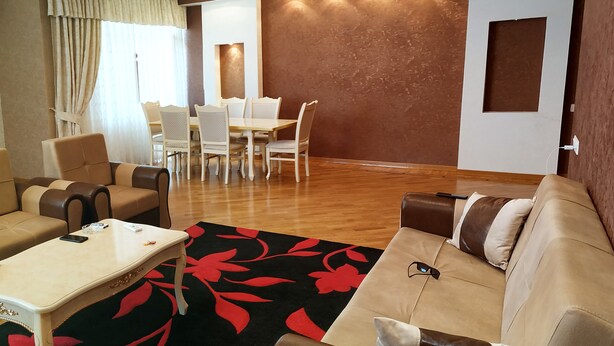 A modern living room with a sofa, coffee table, and a dining area with chairs and a table. - Bakuvi Tourist Apartment B096 (Baku)