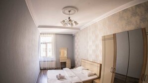 A bedroom with a bed, a wardrobe, a desk, and a window with curtains. - Bakuvi Tourist Apartment B098 (Baku)